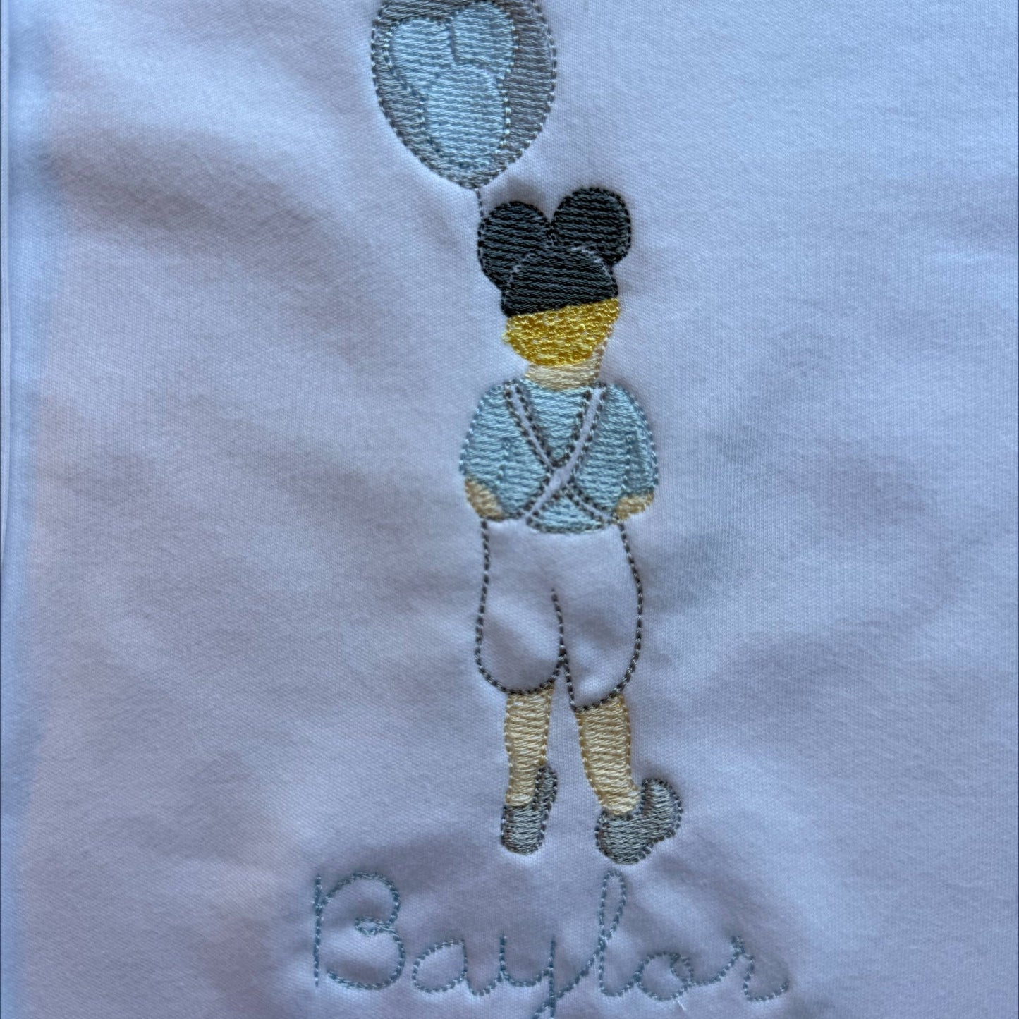 grandmillennial boy with light blue outfit and disney mickey ear balloon on a white background