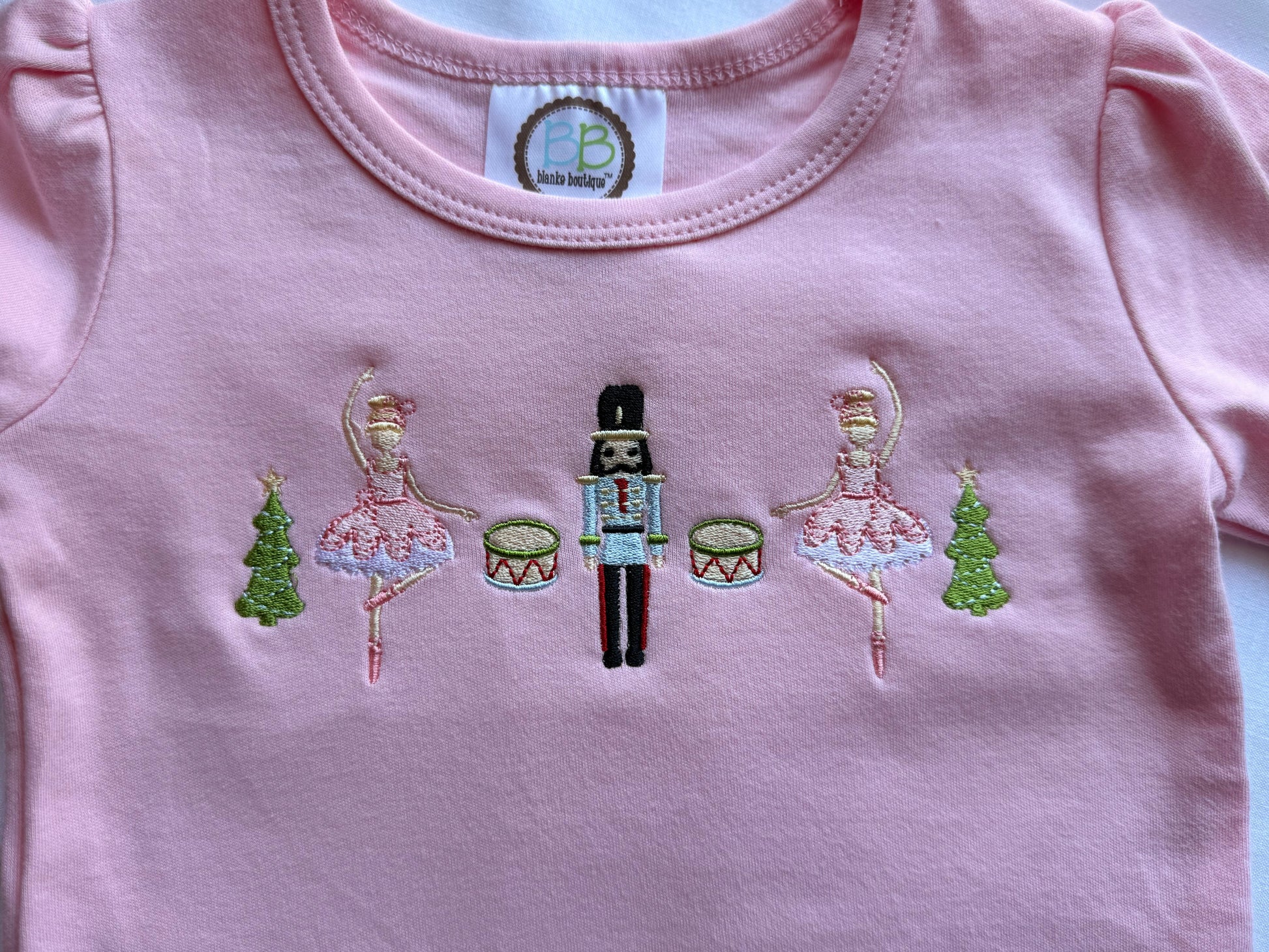 Pink garment with embroidered designs on a white background